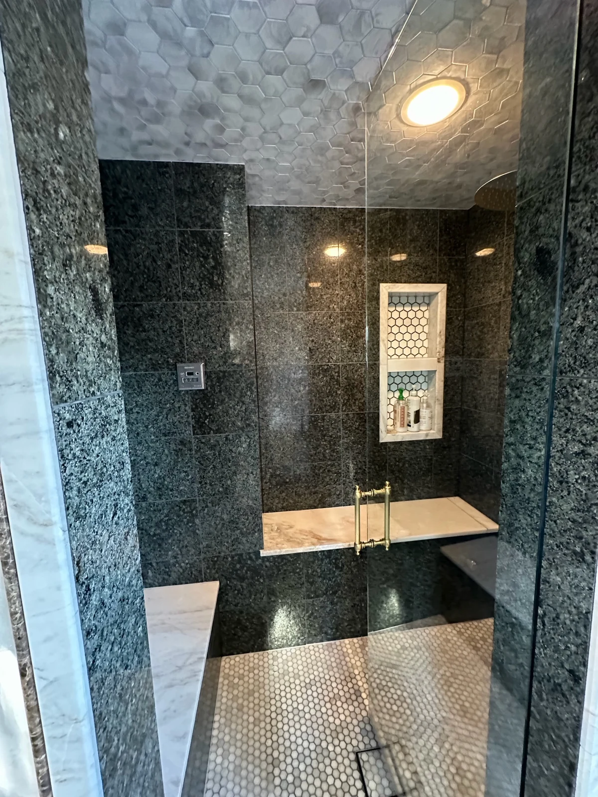 Custom luxury steam shower remodel in Redmond WA featuring polished granite walls, hexagon marble mosaic ceiling, floating marble benches, and digital steam controls